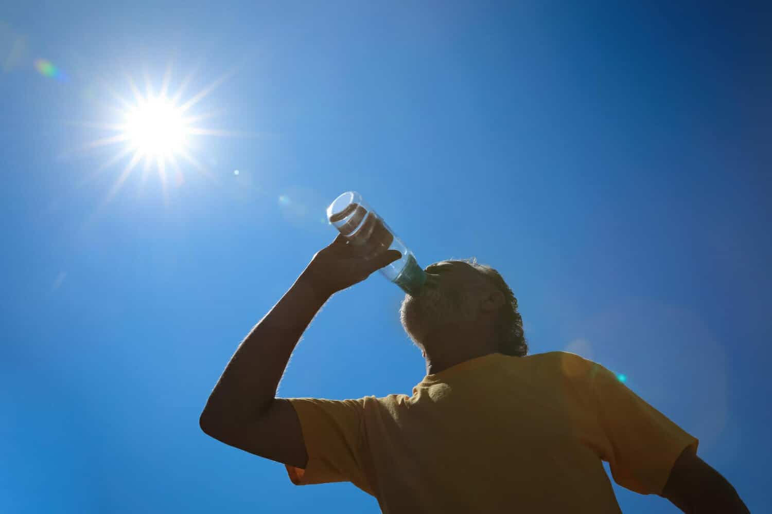 uomo anziano che beve acqua per prevenire il colpo di calore all aperto vista ad angolo basso