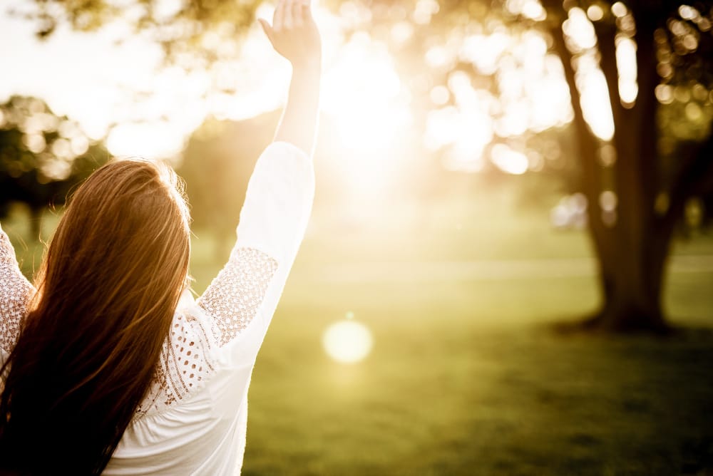 closeup from female holding her hands towards sky with blurred background