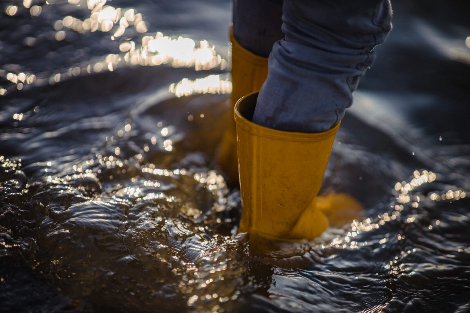 persona in jeans blu denim e stivali gialli in piedi sull acqua