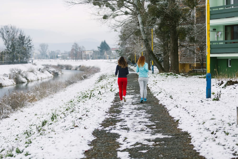 rear view two female friends jogging road winter