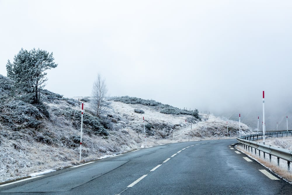 road surrounded with snowy mountains covered fog