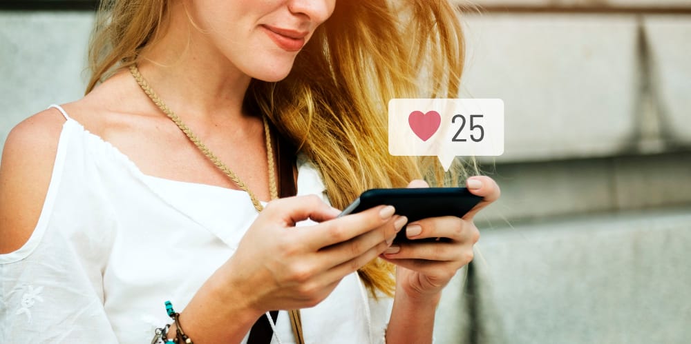donna felice che utilizza i social media sul suo smartphone