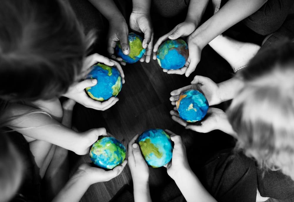 il gruppo di varie mani dei bambini che tengono le sfere foggianti a coppa del globo insieme